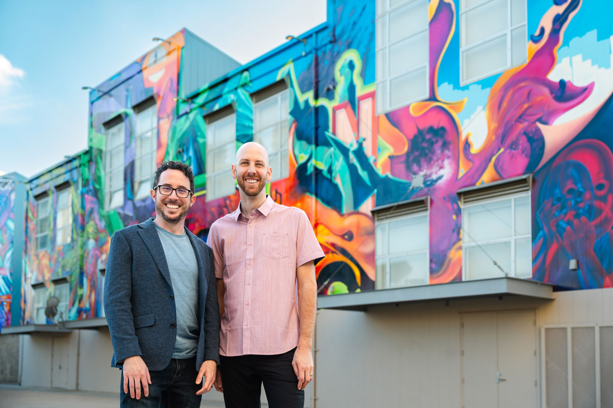 corey and parker standing next to each other in front of a colorful building